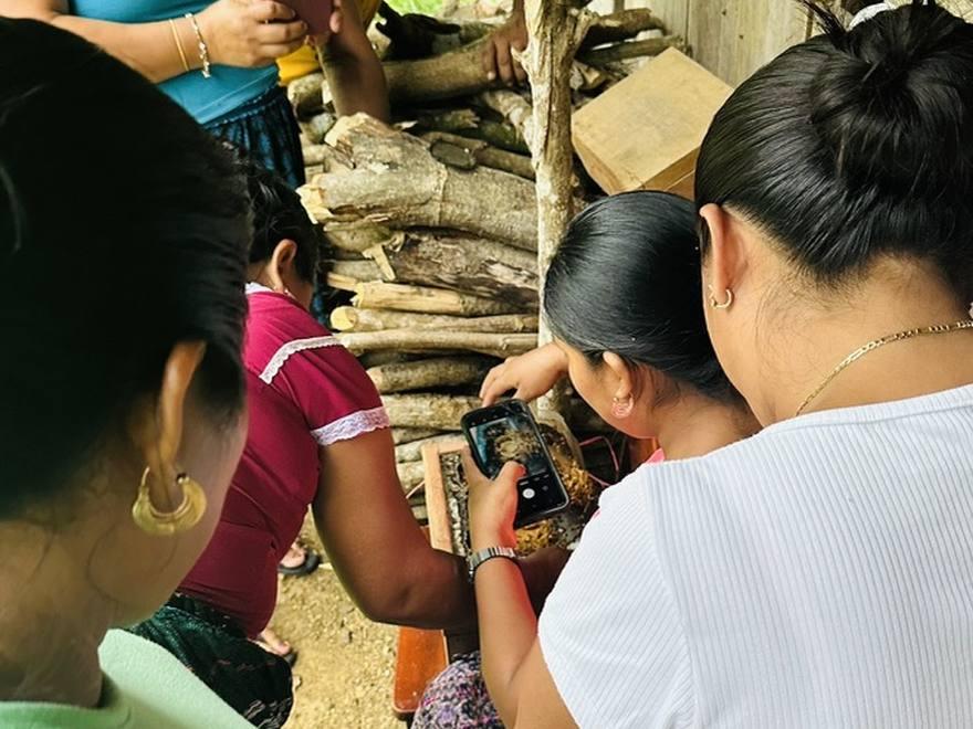 Komonil team and community members gathered around a hive box during a field training session